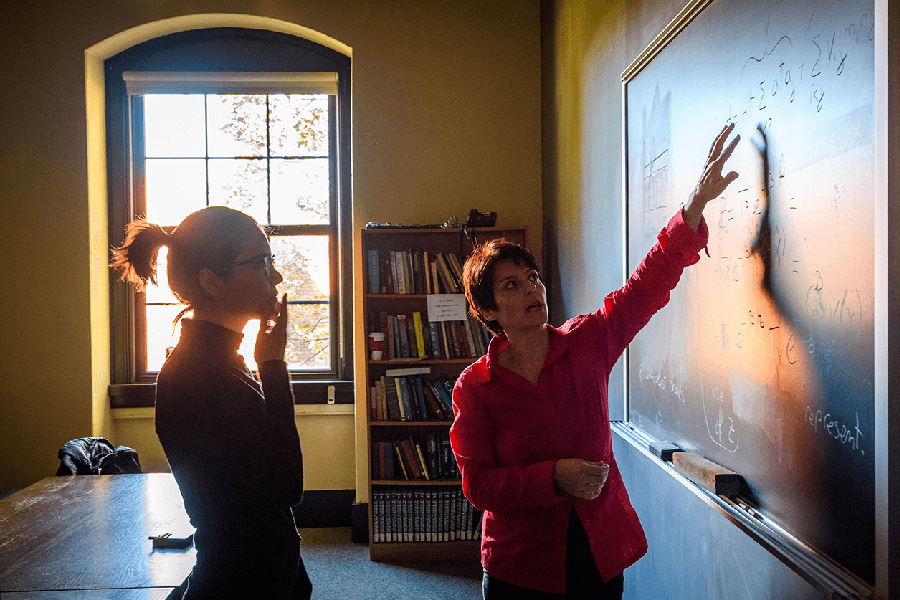 faculty with student member in front of chalk board