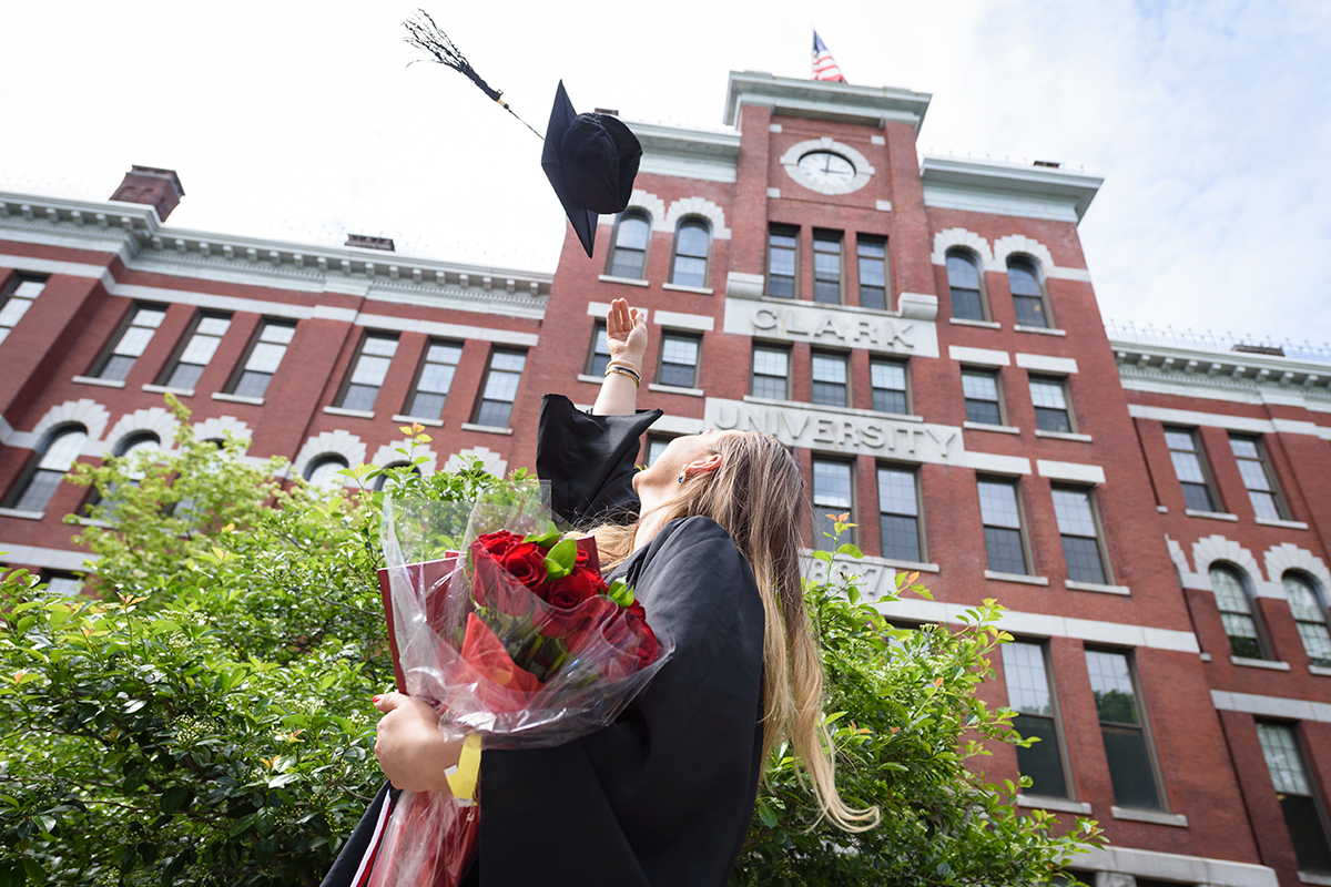 girl tossing graduation cap up in the air
