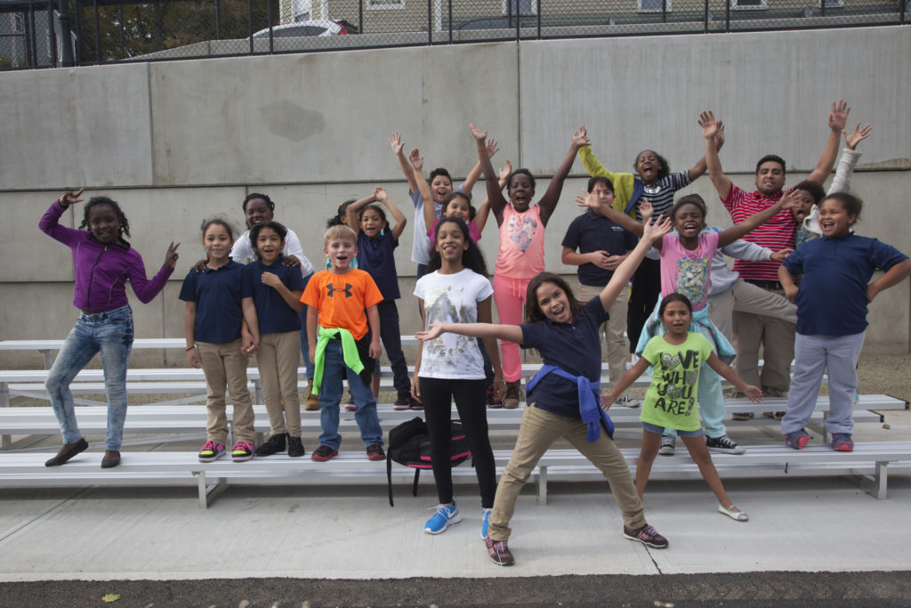 young students posing in front of school
